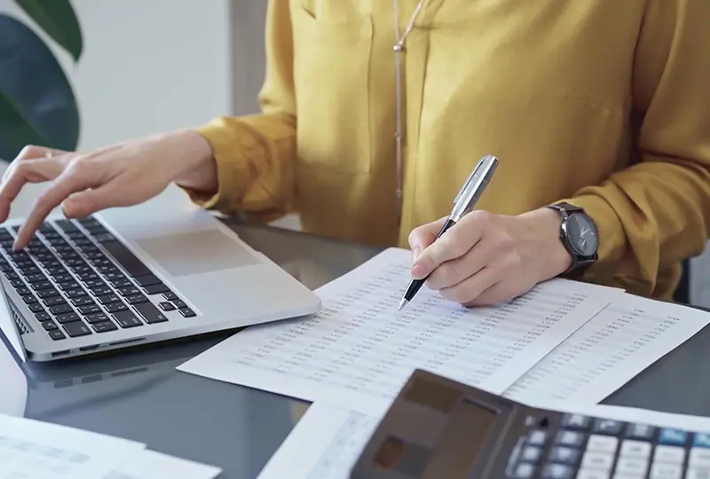 Person working on laptop and financial documents.