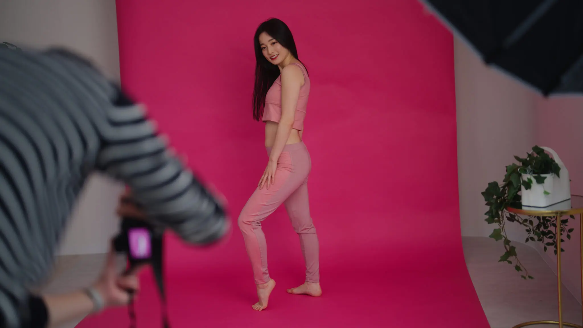 Behind the scenes footage of a photo shooting. Photographers videographers female models director and make-up artist are working together in a studio.
