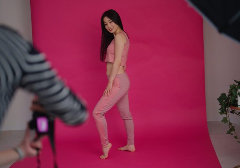 Behind the scenes footage of a photo shooting. Photographers videographers female models director and make-up artist are working together in a studio.