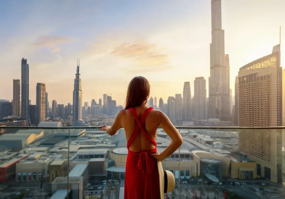 Woman overlooking city skyline at sunset.